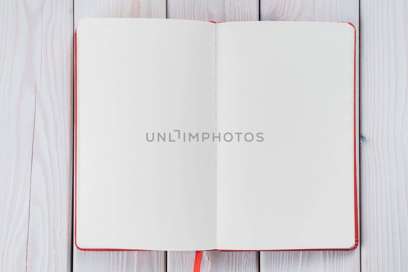 Red diary, text book with white paper pages on wooden table background. Making notes in empty workbook on office desk. Personal organizer as reminder. Blank and template. Copy space, flat lay