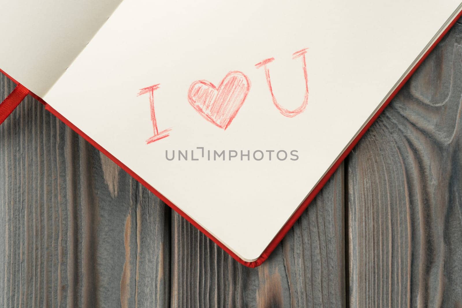 Red diary book with white paper with sign label I love you in the corner of page with red shaded line heart. Love letter message for beloved, confession and feelings for Valentines Day. Top view