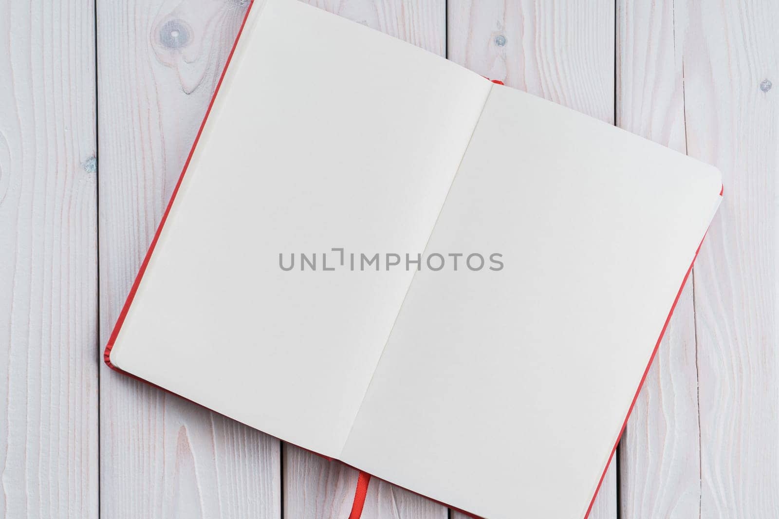 Red diary, text book with white paper pages on wooden table background. Making notes in empty workbook on office desk. Personal organizer as reminder. Blank and template. Copy space, flat lay
