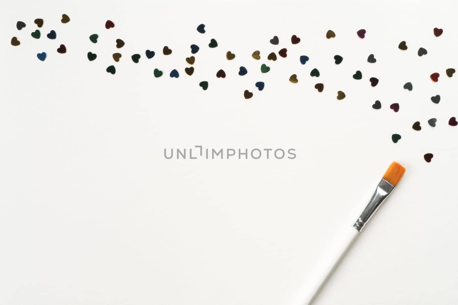 Paintbrush draw and mark small colorful paper hearts on white background. Decorative foil and paper elements for decoration. Glowing and shining art. Valentines day make up. Top view, copy space