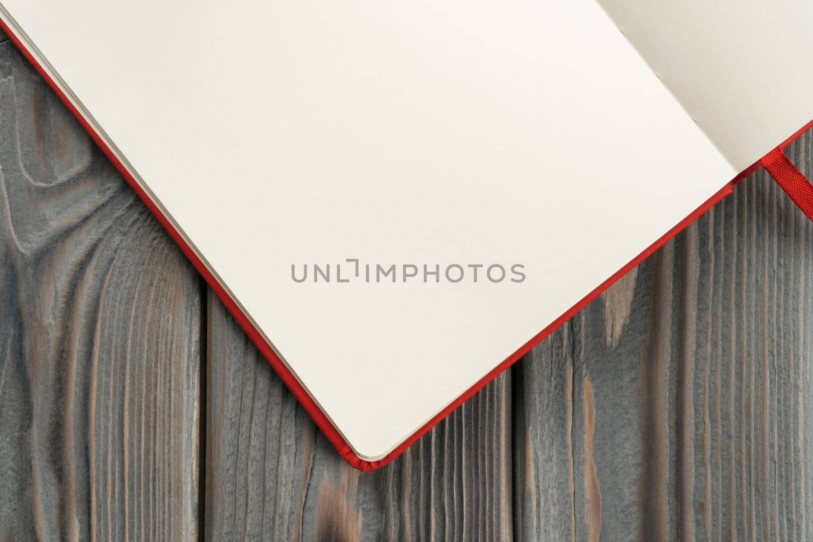Red diary, notebook corner of white paper pages on dark wooden background. Making notes in empty workbook on office desk. Personal organizer as reminder. Blank and template. Copy space, top view