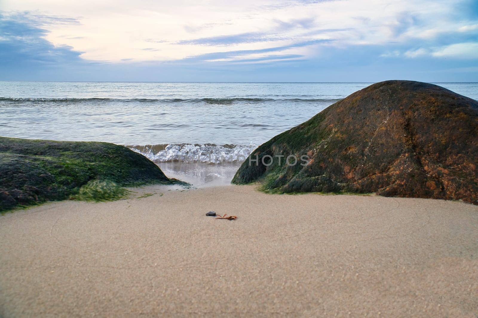 Big stone on the sandy beach in front of the sea with clouds in the sky. Denmark in Scandinavia. Landscape shot from nature in the north