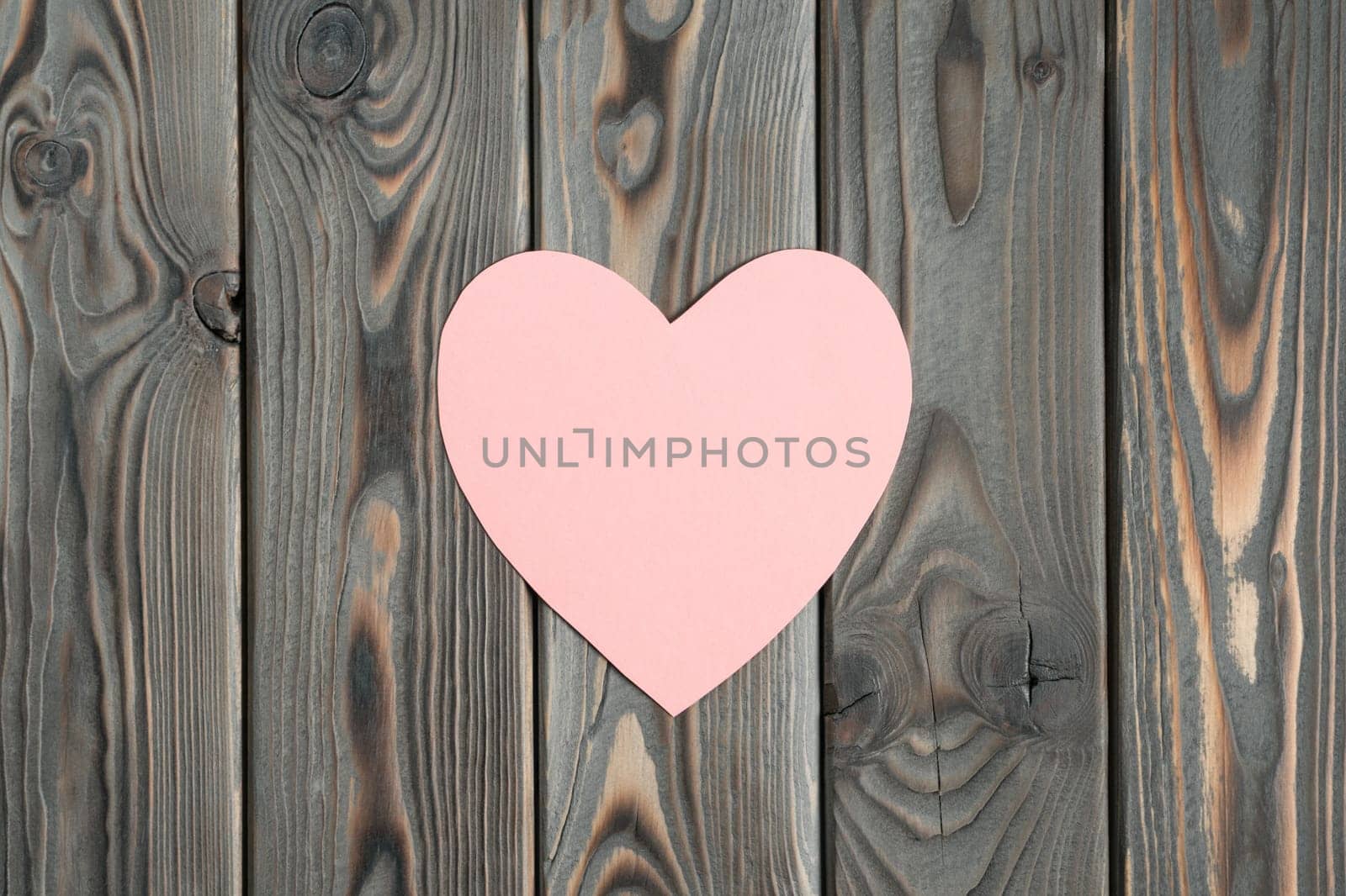 Pink paper heart on dark wooden plank background. Falling in love and confession in saint valentines day. Be my valentine. Love message and romantic holiday celebration. Mockup, copy space, flat lay