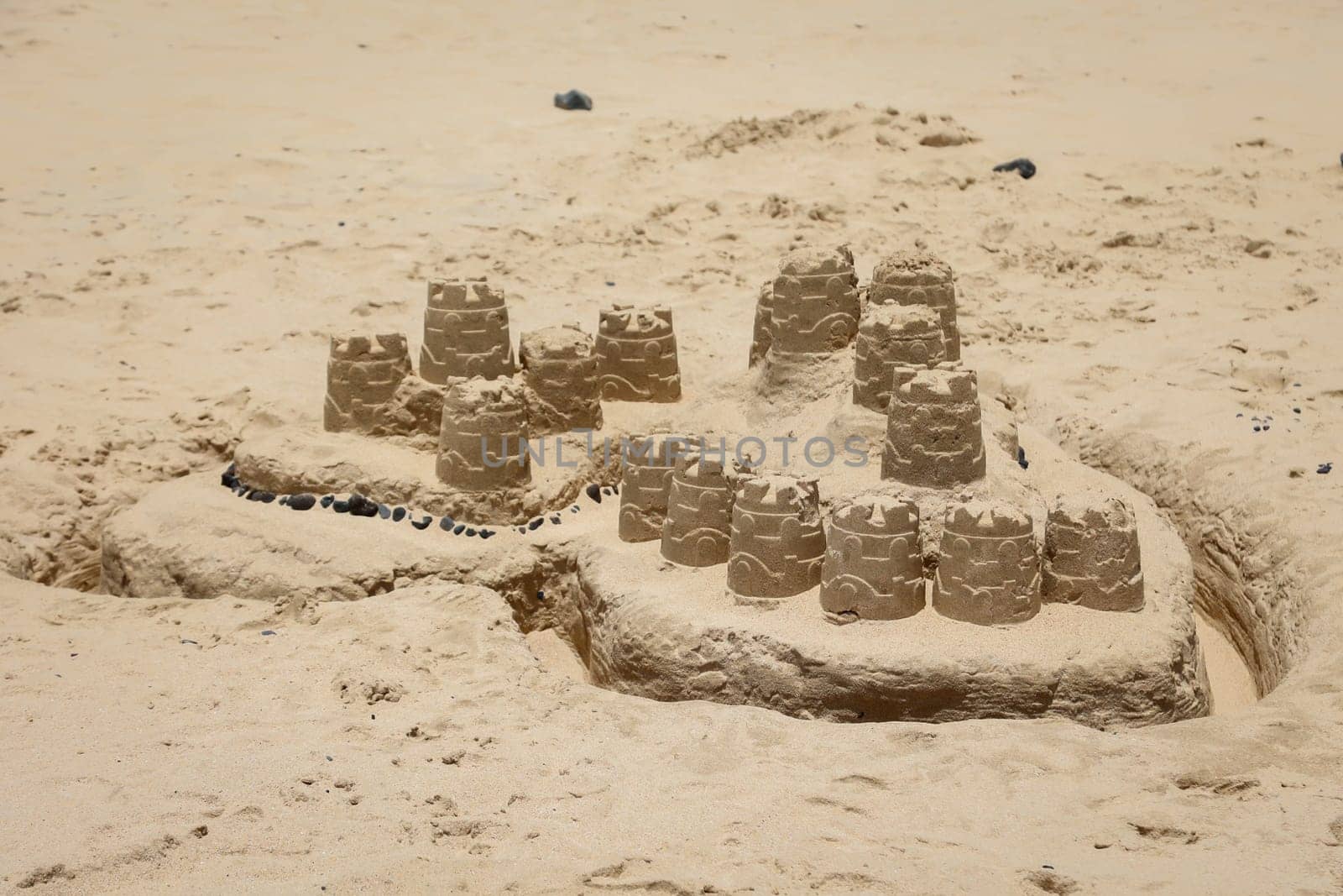 A big sandcastle built on the beach with buckets and ramekins.