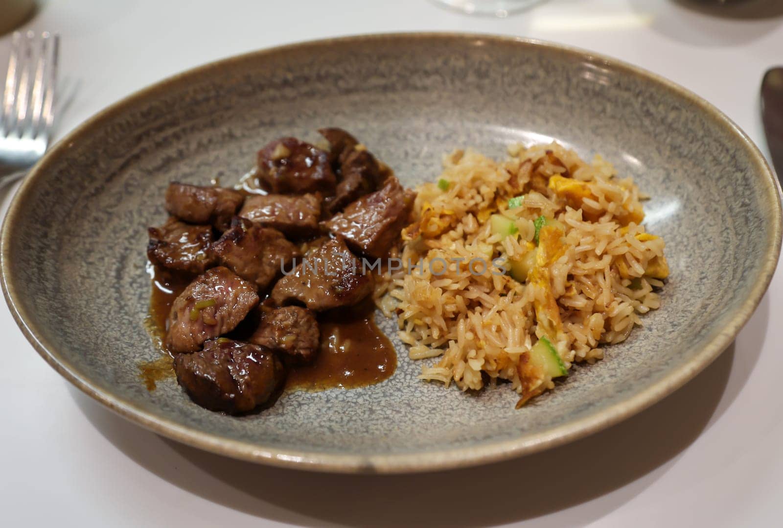 Cut up well prepared fillet of beef with rice and vegetables on a plate.
