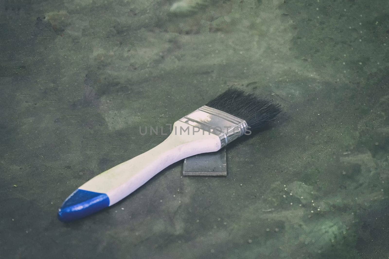 White paint brush on the gray-black cement floor