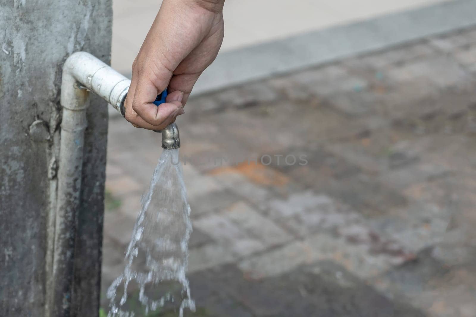 Old faucet and hand are open water.