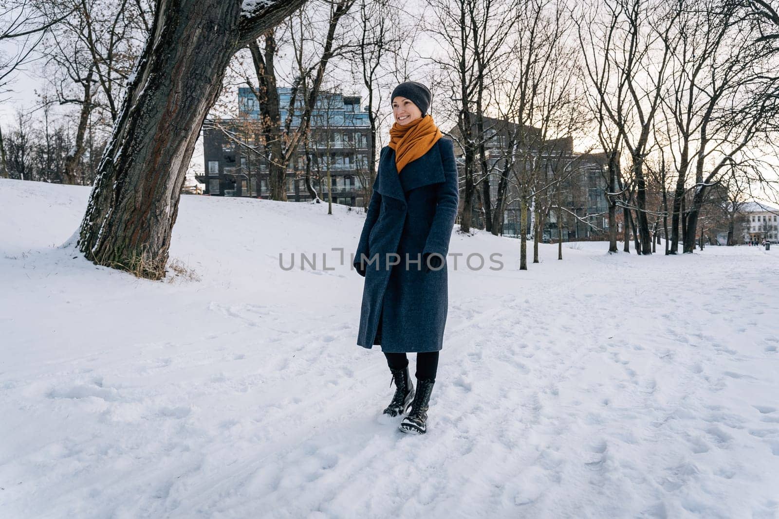 A woman walks on the snow-covered ground and smiles.
