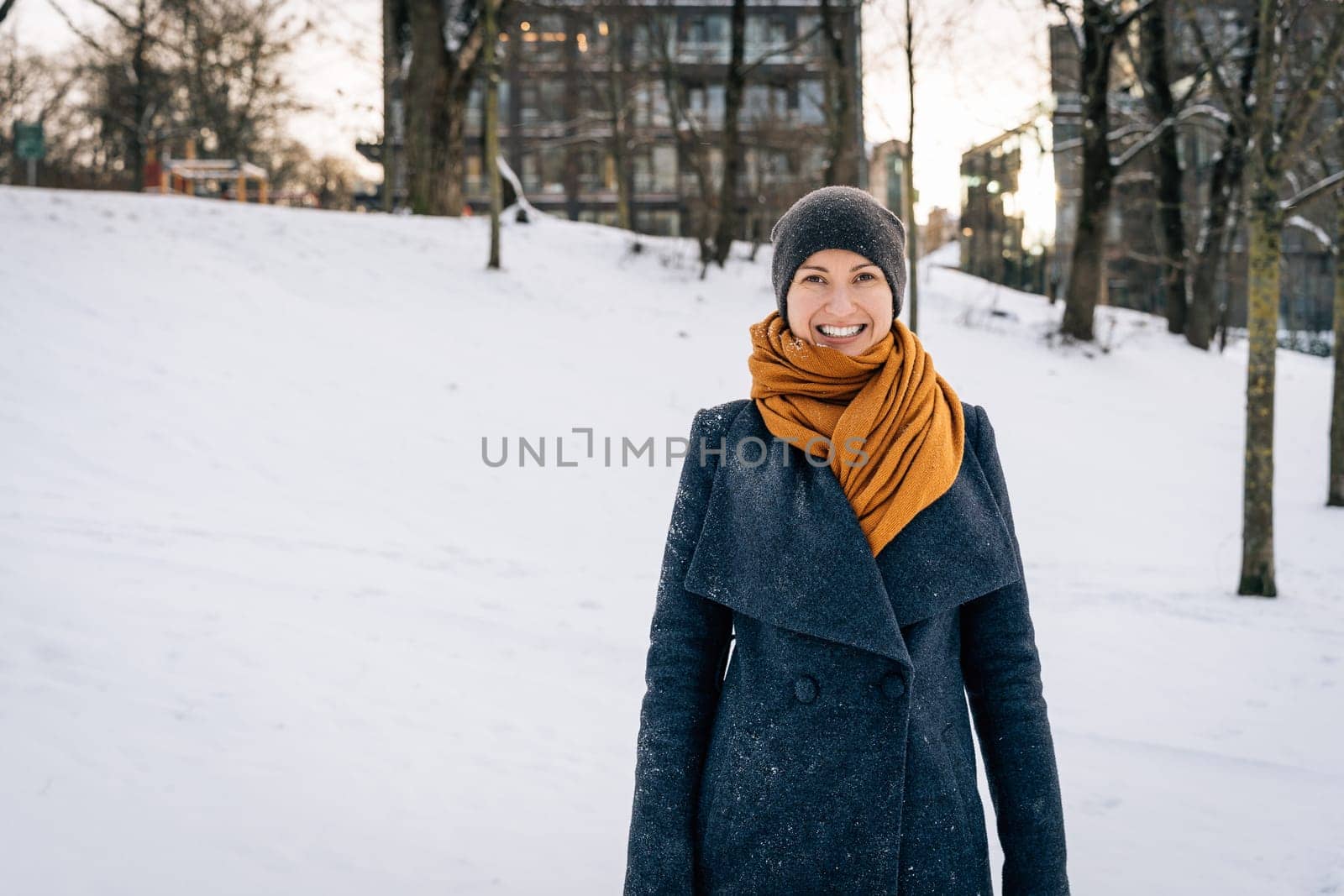 A young woman in winter clothes smiles broadly looking into the camera.