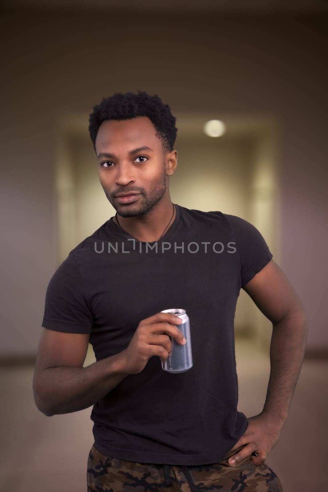 cool attitude man drinking soda holding can cola in hand wearing black t-shirt indoor