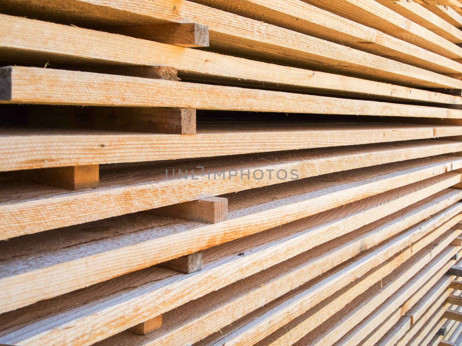 Format-filling perspective view of new softwood boards stacked parallel on top of each other.