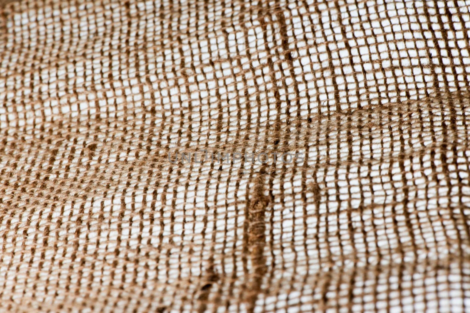 Full-frame view of coarse textile fabric with sharpness gradient on a white backlit background.