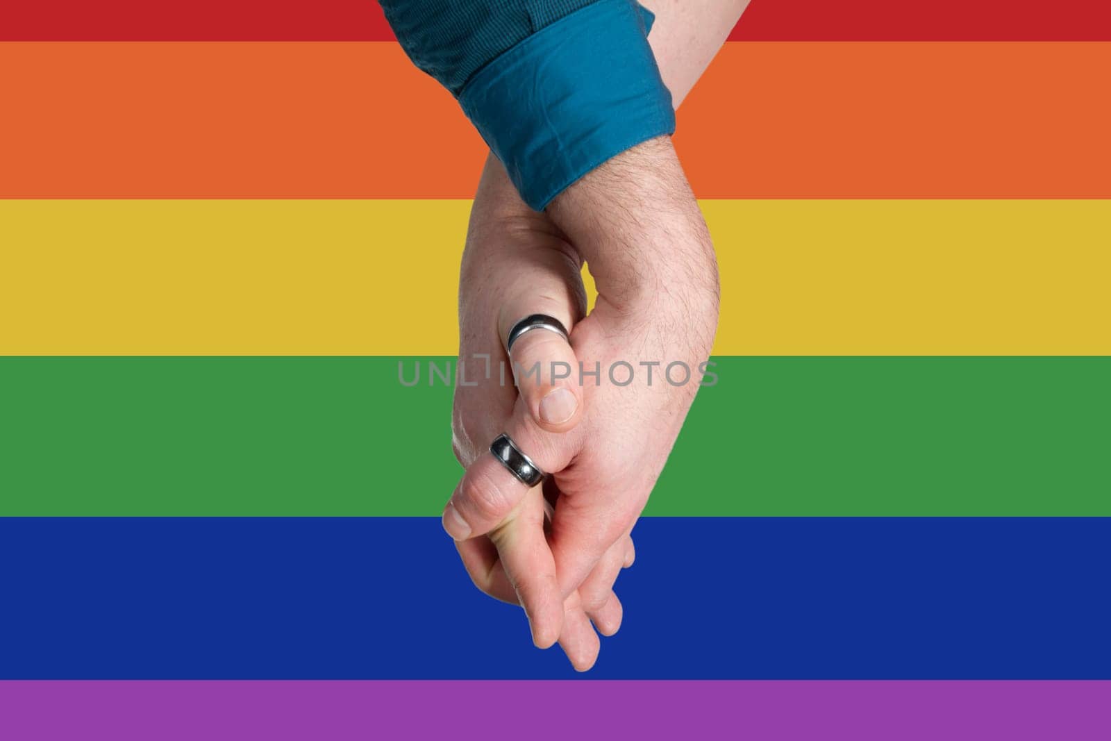 Homosexual couple hands into each other on rainbow flag background