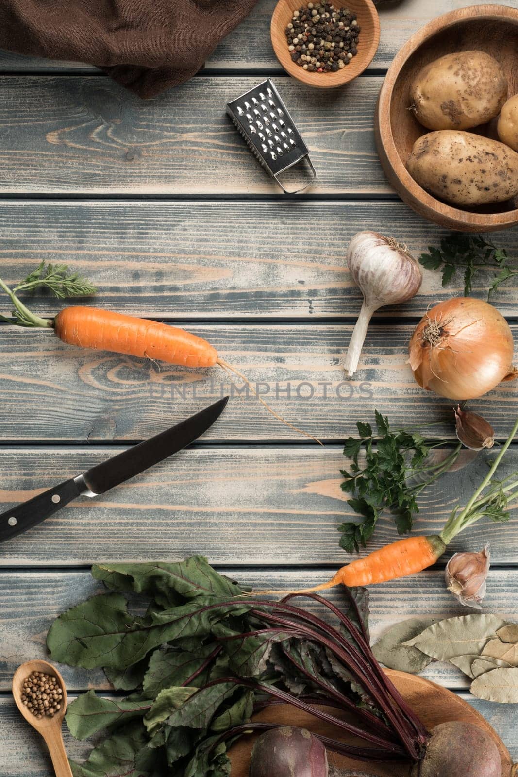 Knife for peeling carrots, flat lay. Kitchen tools for cooking. Mix of raw fresh organic vegetables on wooden table. Healthy food, ingredients. Zero waste, eco concept. Separate waste collection.