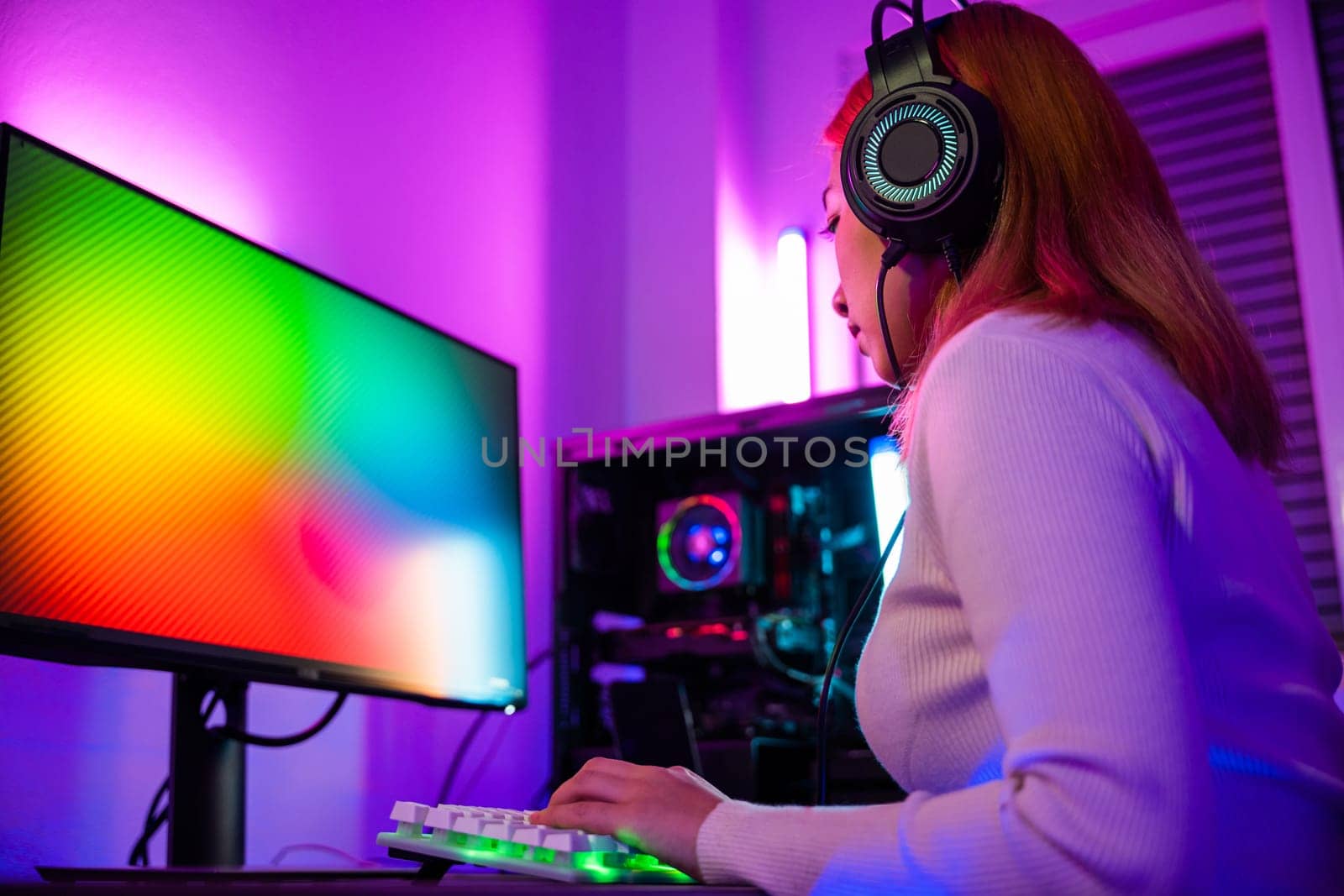 Asian woman gamer wearing gaming headphones holding joystick console to play video game and streaming online on computer PC neon light at home, tournament player E-Sport concept