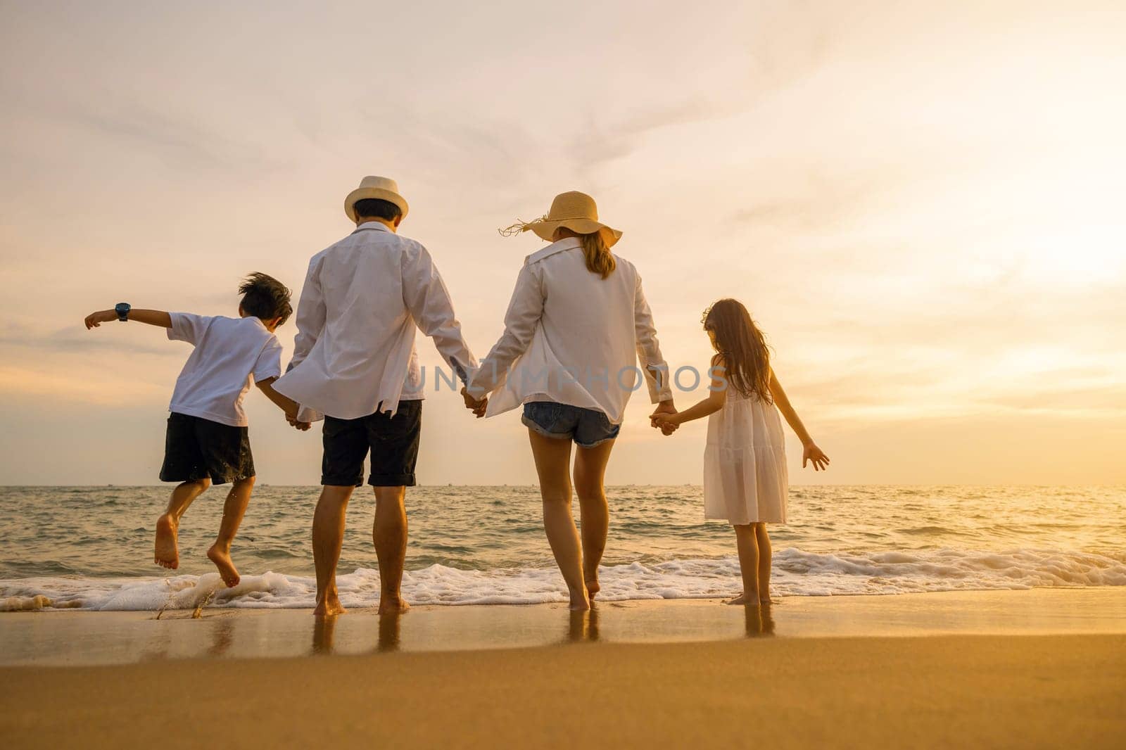 Silhouette of family holding hands live healthy lifestyle on beach, Happy Asian family have fun jumping together on beach in holiday sunset time, Back people enjoying travel trip and summer vacations