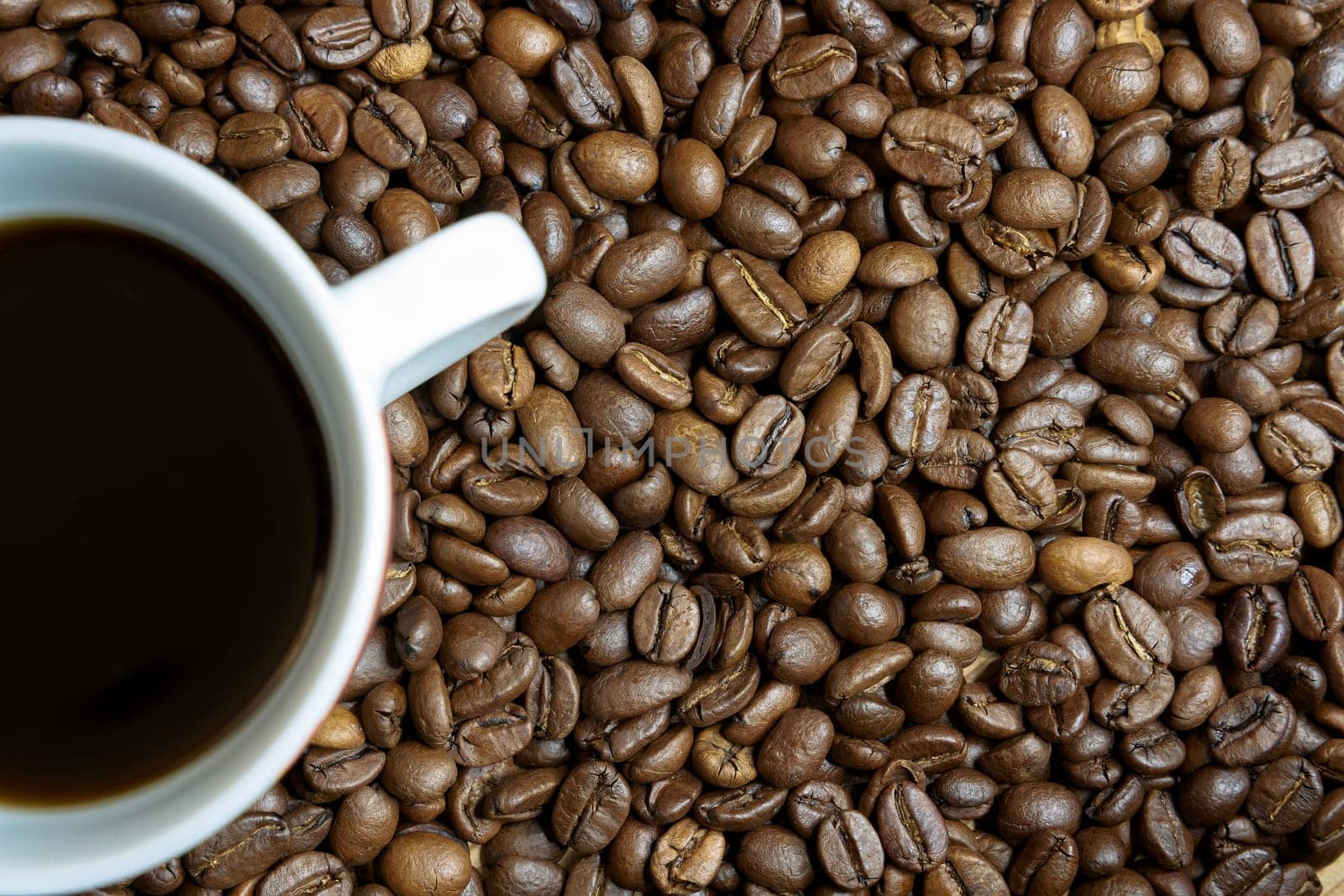 roasted coffee beans and a cup with coffee on a table