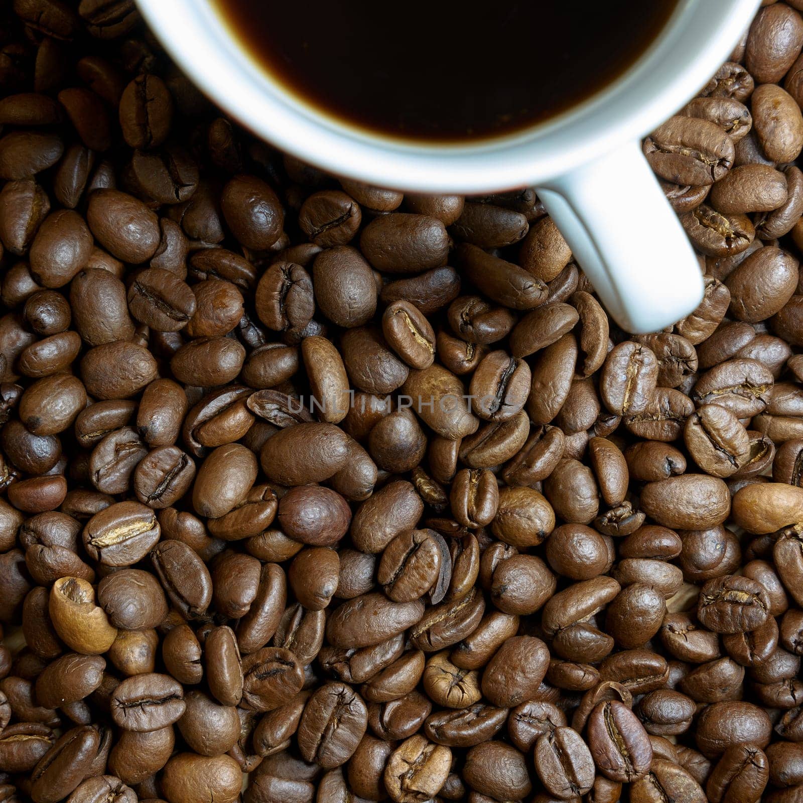 roasted coffee beans and a cup with coffee on a table