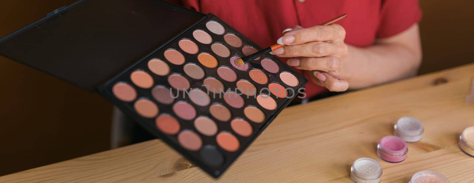 Close-up of woman holding makeup brush and blush and eyeshadow palette - beauty and cosmetics
