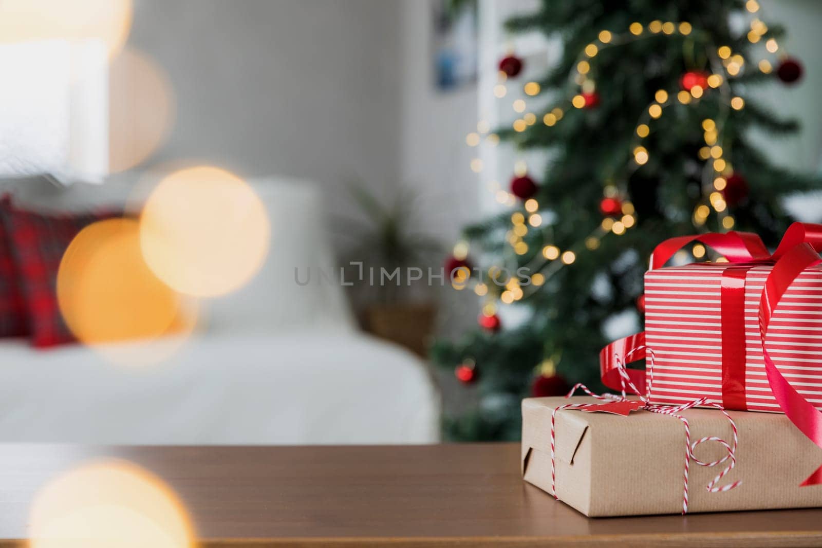 Christmas, New Year background with copy space for design. Empty tabletop surface, blurred decorated Christmas fir tree composition, bokeh lights effect, boxes with gifts. Mockup for product montage