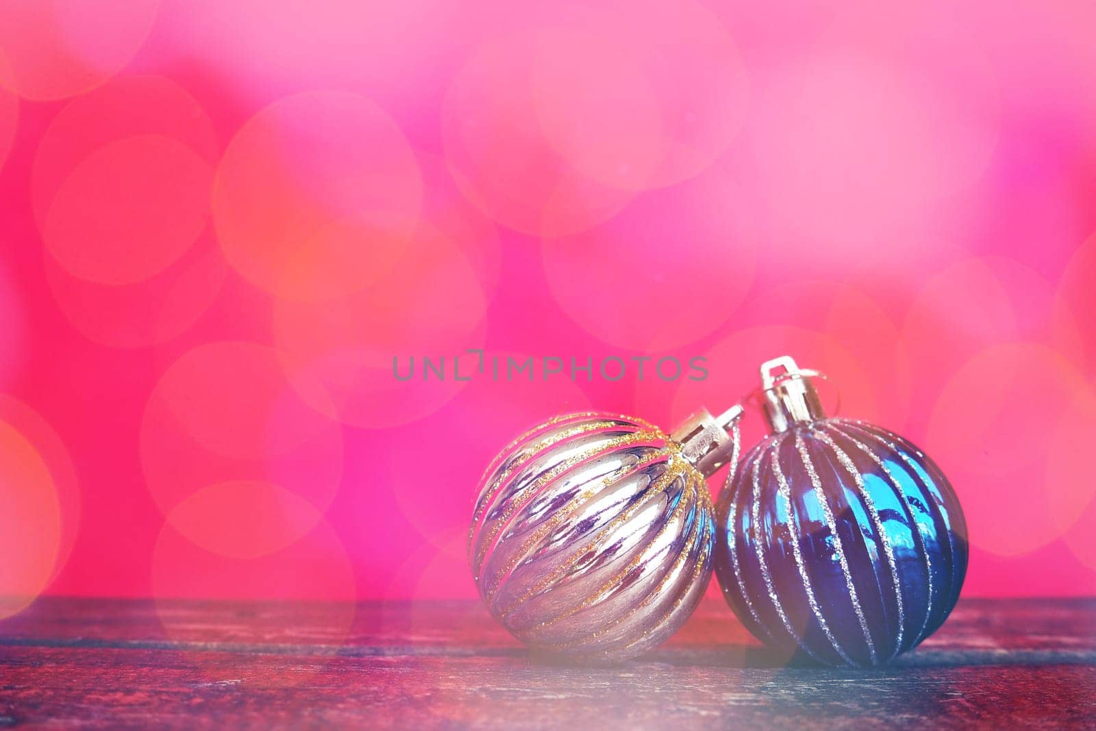 Christmas balls on a red-pink background. Glare bokeh. New Year or Christmas card. White and blue Christmas decorations for the holiday. Copy space.