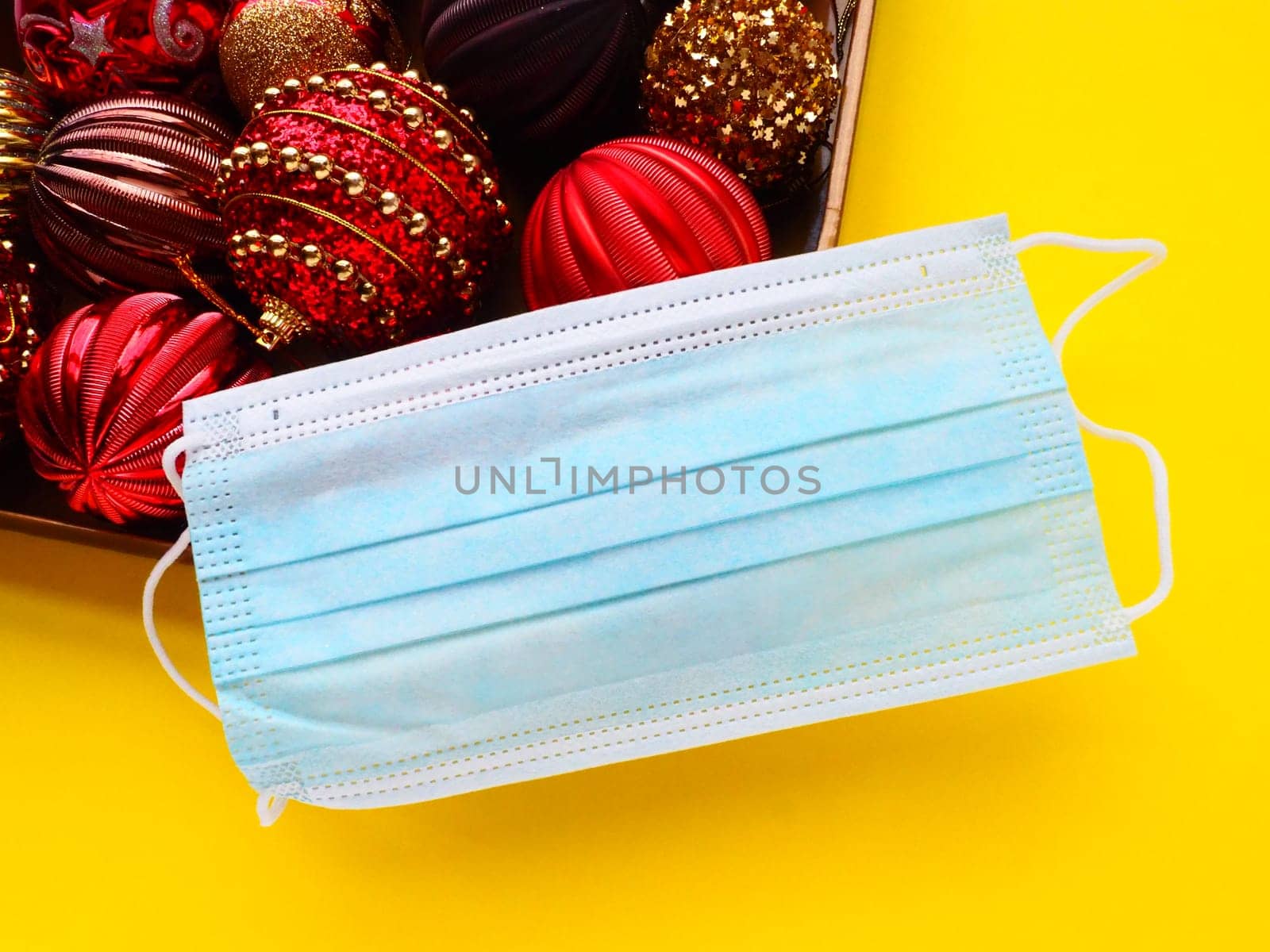 Protective surgical mask on a box with Christmas decorations. Covid New Year. Holiday restrictions and lockdown concept. Corona virus epidemic covid-19.