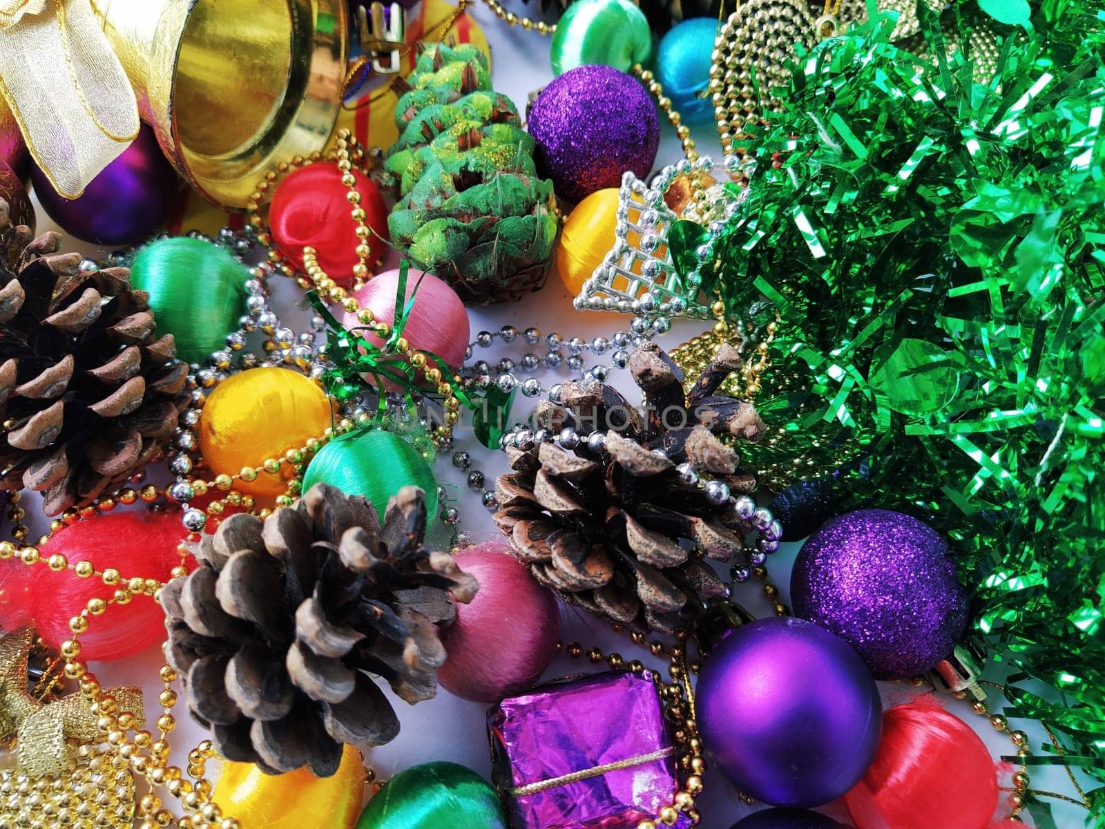 Christmas decoration collection. Beautifully arranged shiny bright Christmas tree decorations, green foil, gifts. Red, purple, yellow colorful decor elements for New Year and Christmas.