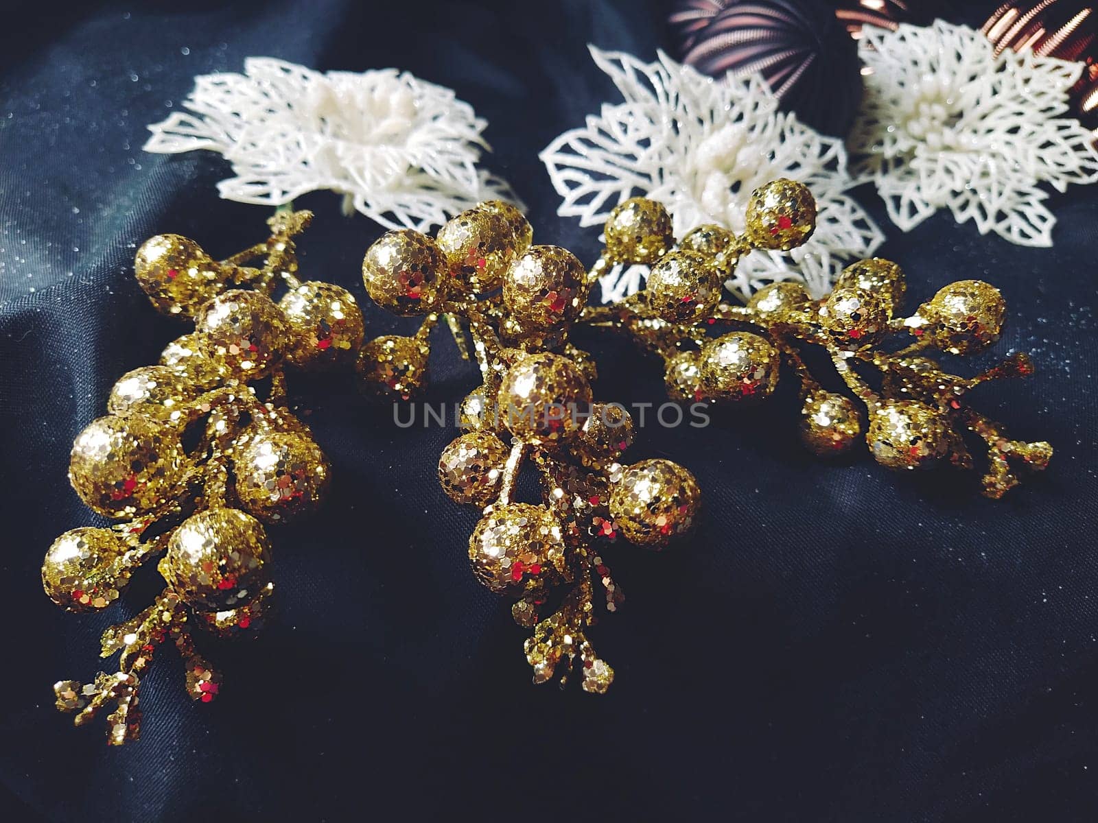 card for the new year and christmas with decorations, Christmas decorations and sparkles on a black background. Shiny white flowers and snowflakes, golden twigs with berries. Blue haze. Soft focus.