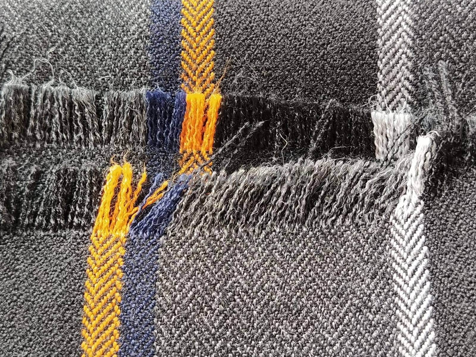Light black-gray folded fabric with orange and dark blue stripes. Ripped, unfinished fabric edge. Interior decoration. Dress fabrics in casual style. Dense material for furniture finishing.