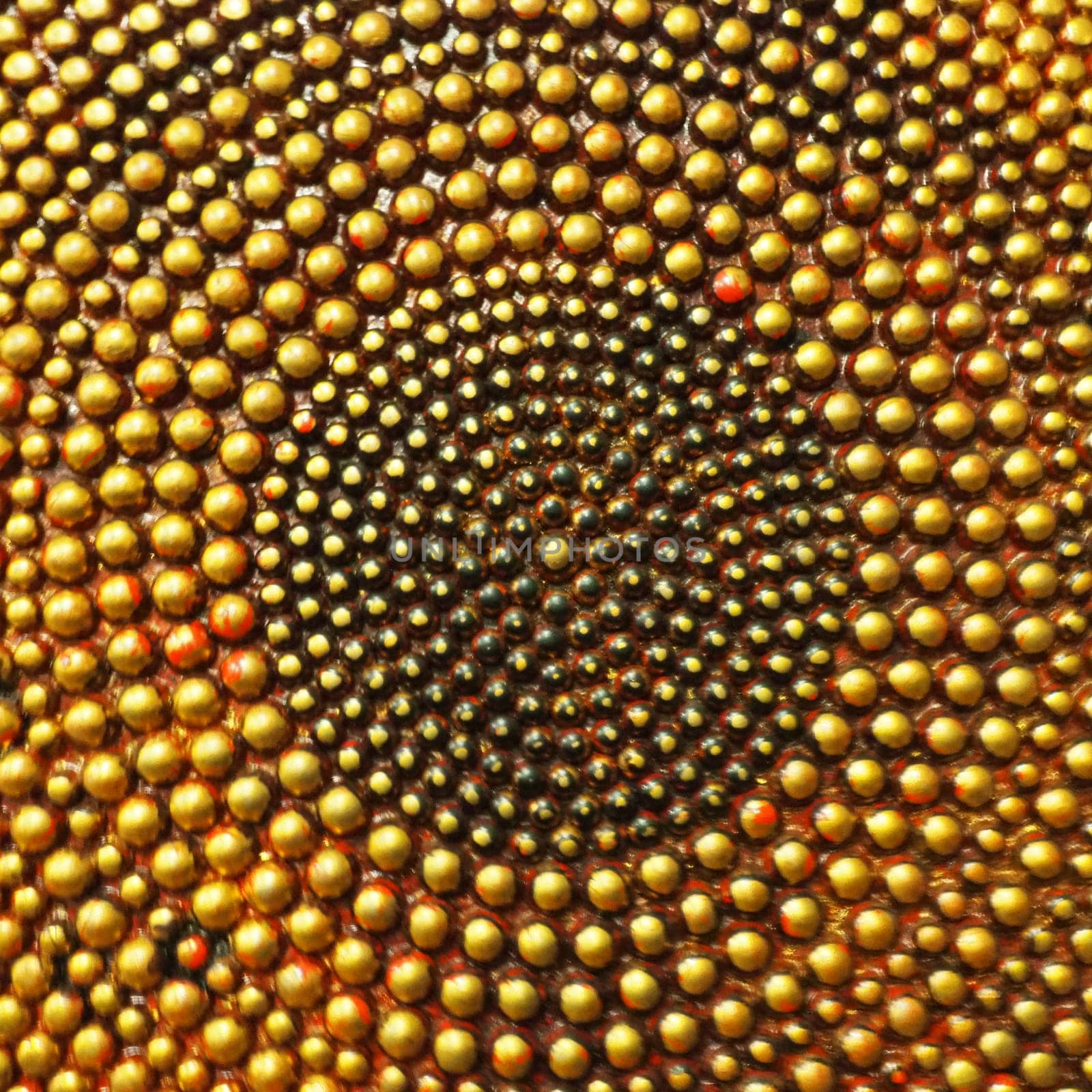 Pimples or spikes made of gold metal. Metal rounded bulges are located in a circle. Symbol of the sun or cycle. Unusual abstract background. The pimples are larger at the edges than in the middle