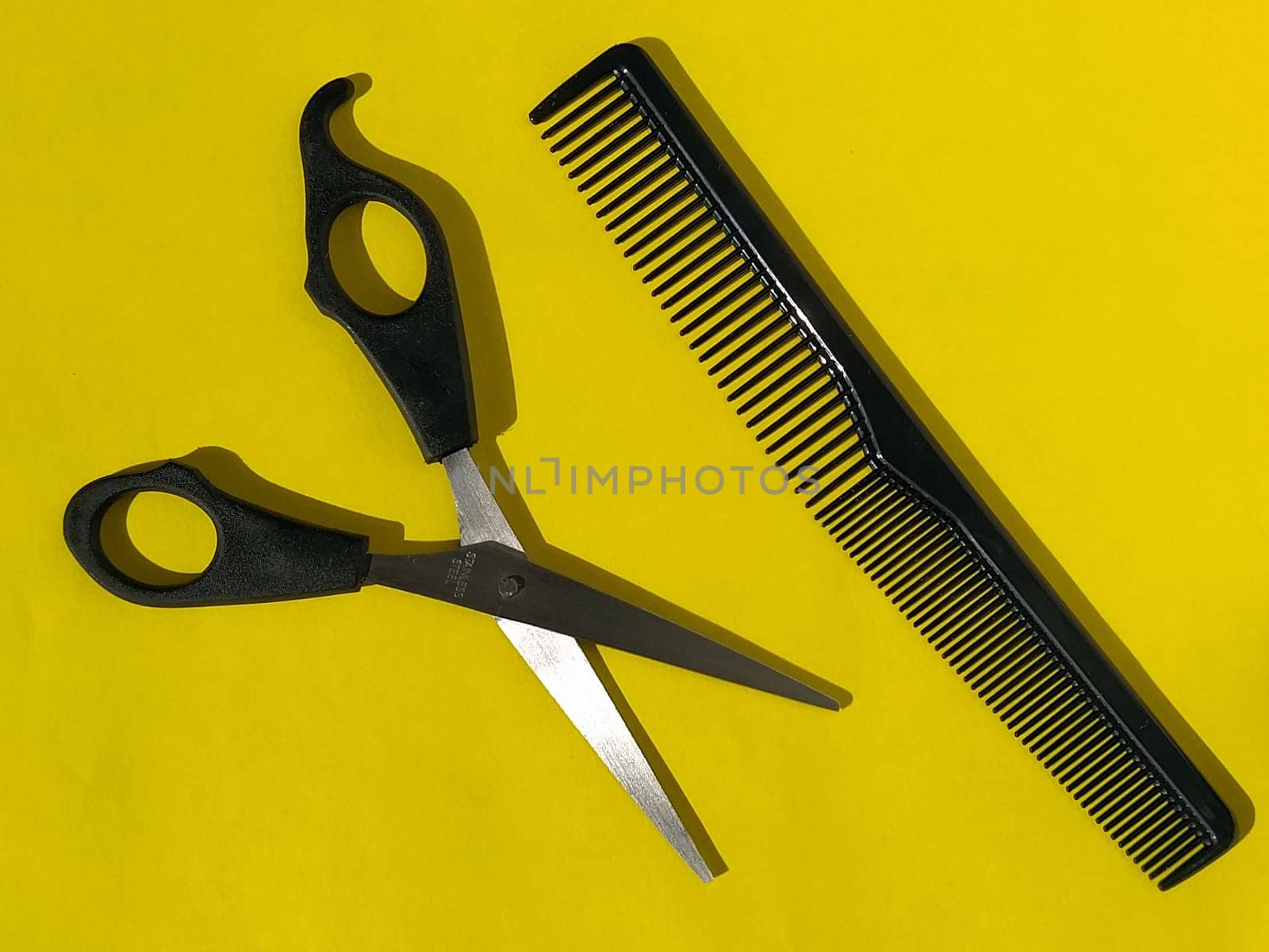 Hairdressing scissors and combs on a yellow background with space for text. Tools of a professional hairdresser. Beauty saloon. Hairdressing equipment.