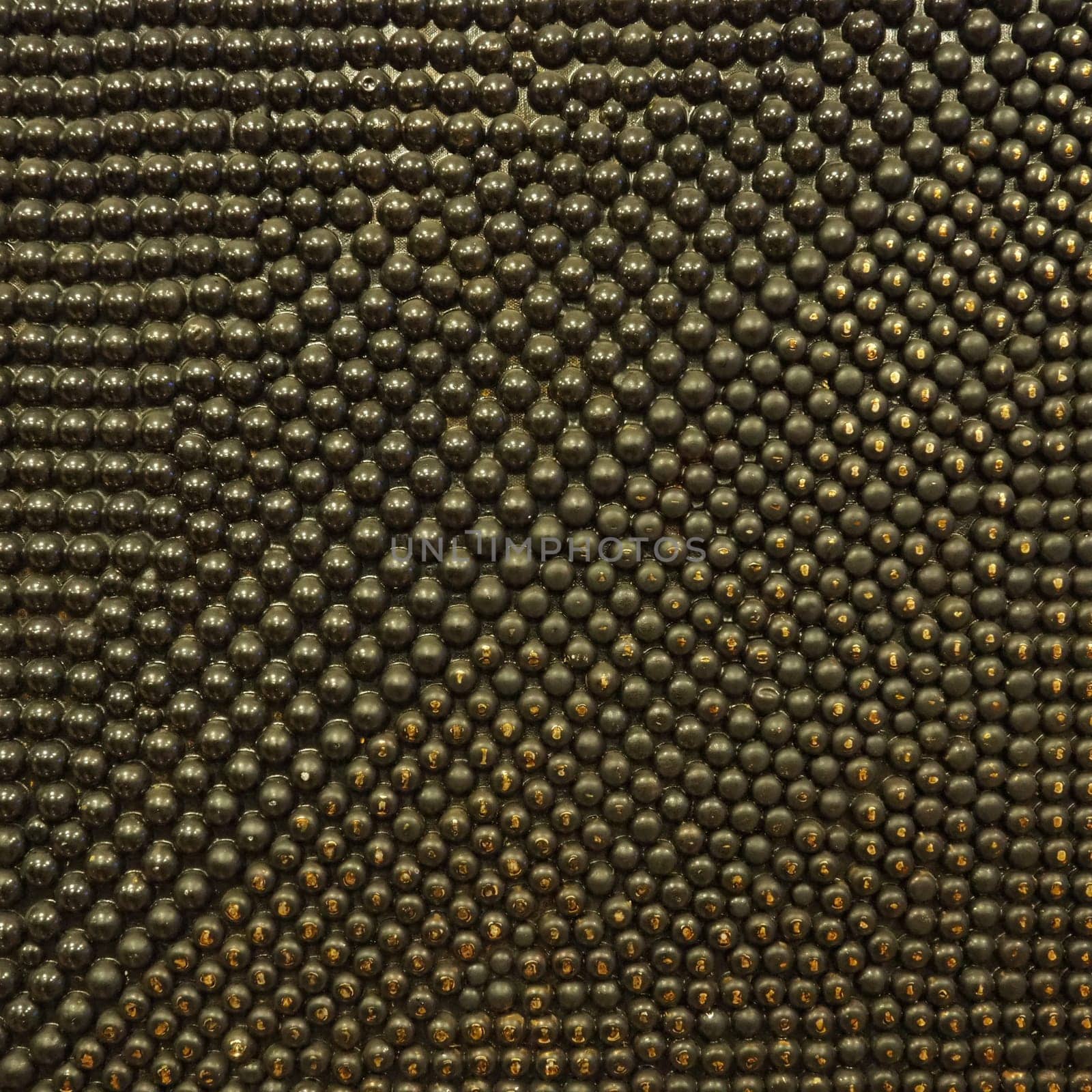 Pimples or spikes made of black and gold metal. Metal rounded bulges are located randomly. Unusual abstract background