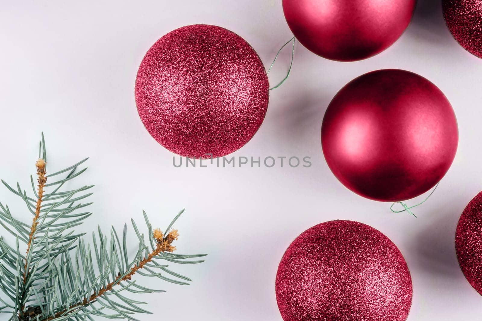 Color of the Year 2023 Viva Magenta. Trendy background of Christmas shiny balls with christmas tree brunch. Fashion carmine shade. Copy space