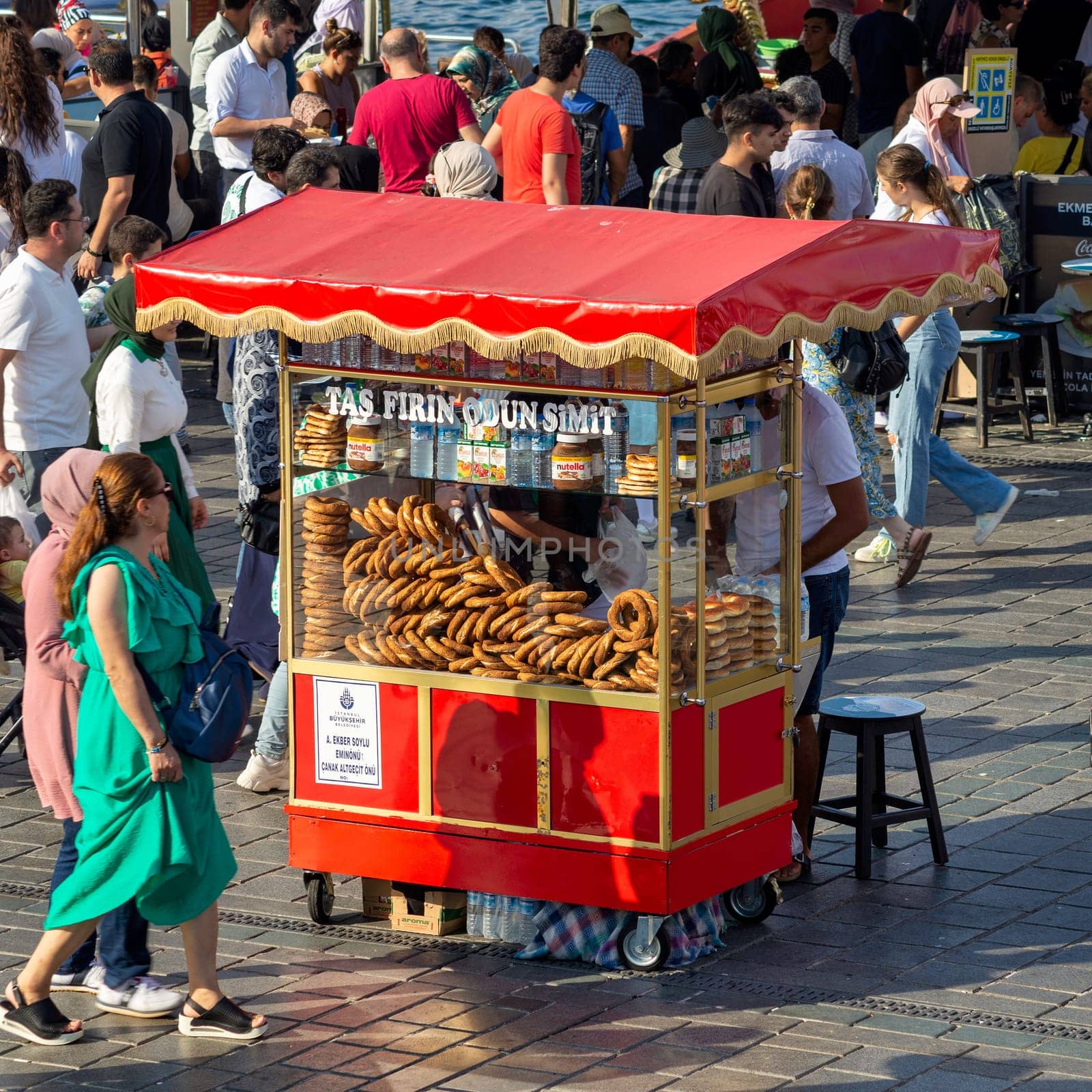 Istanbul, Turkey - August 30, 2022: Male peddler selling simit, on traditional Turkish fast food cart at Eminonu Piazza