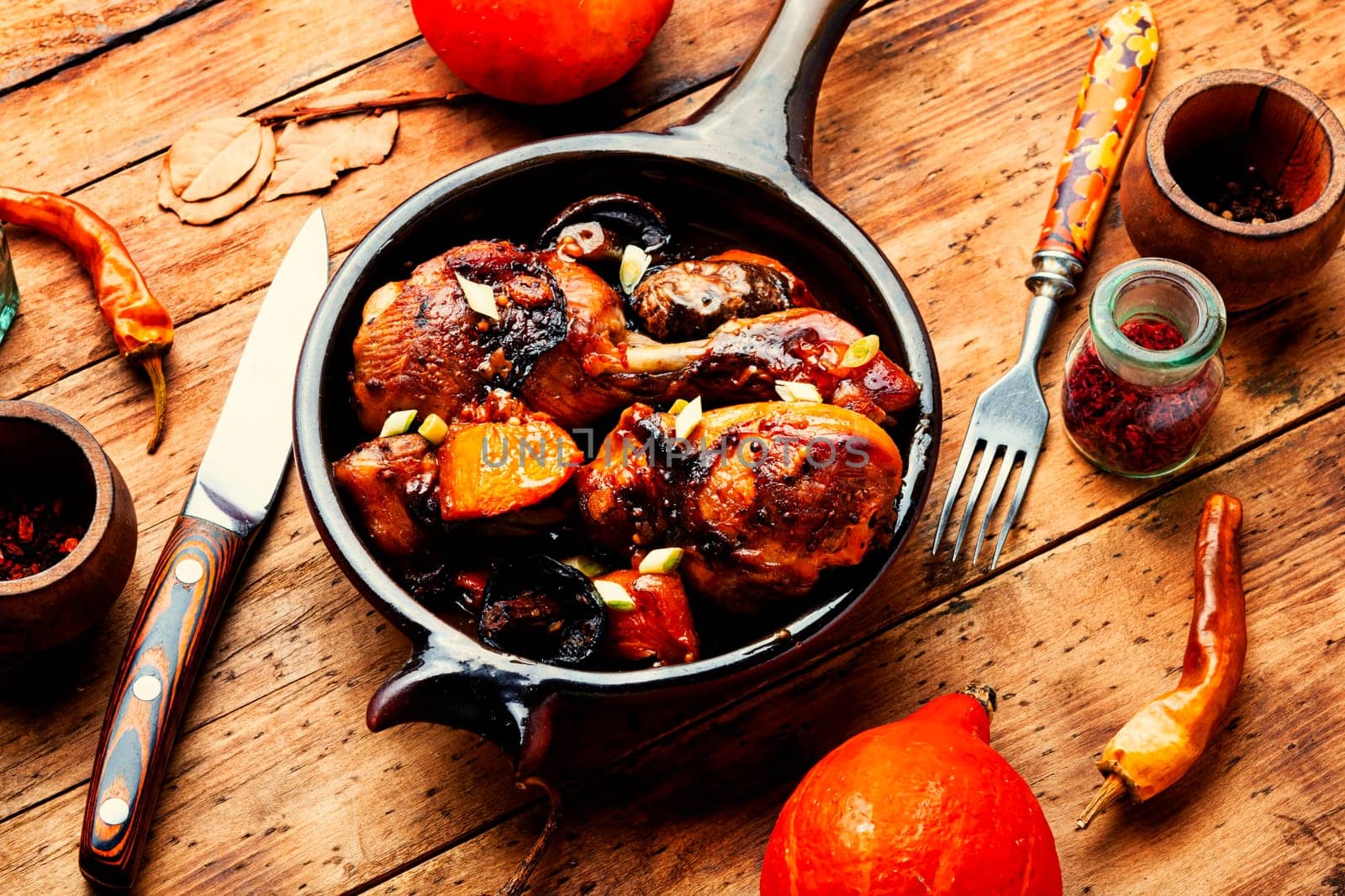Chicken legs roasted with pumpkin on a table decorated with squash