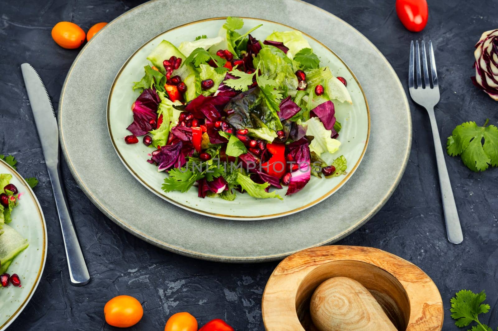 Vitamin salad with greens, pepper, red lettuce and cucumber, decorated with pomegranate.