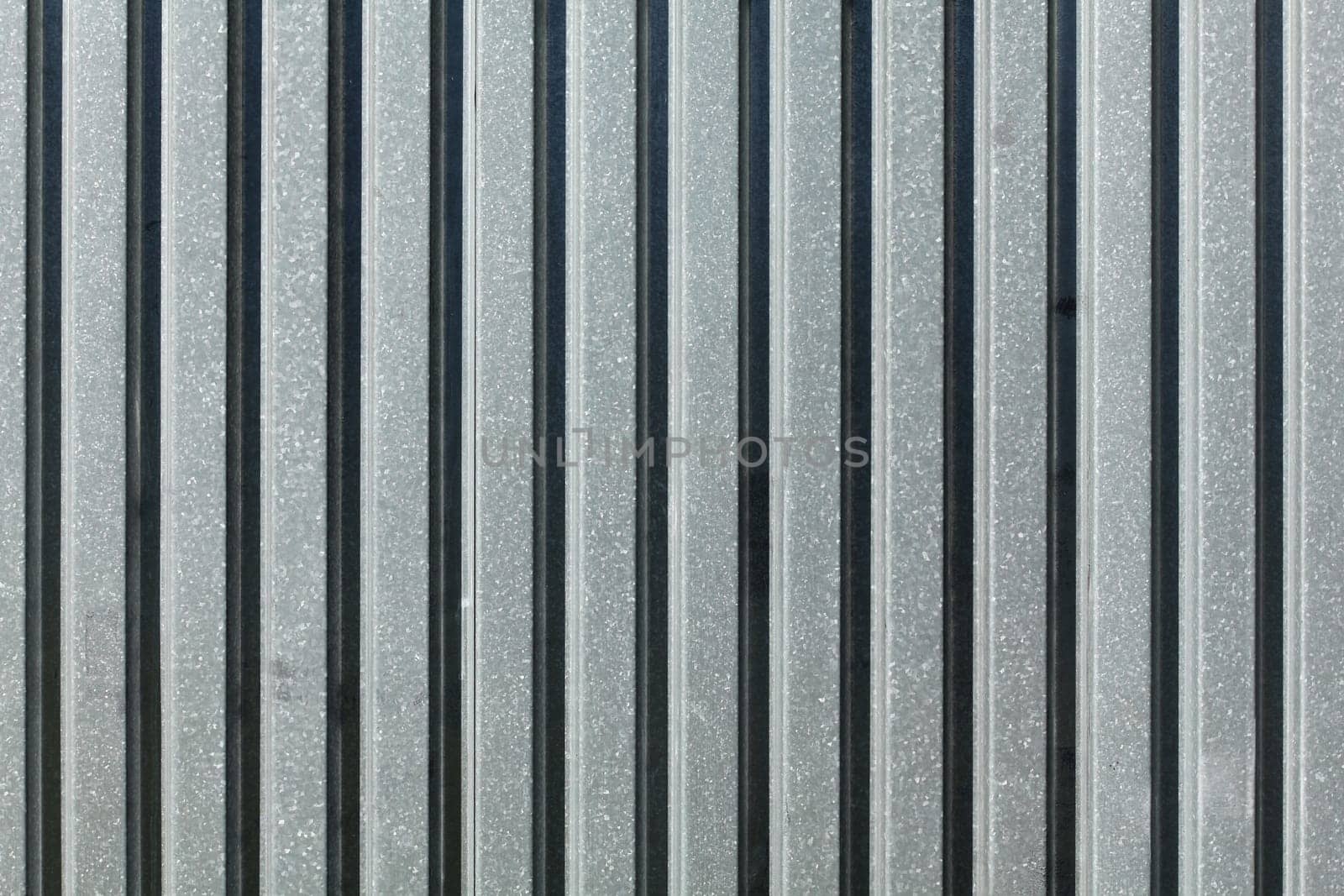 Metal plate fence, sun shining from side. Abstract construction background.