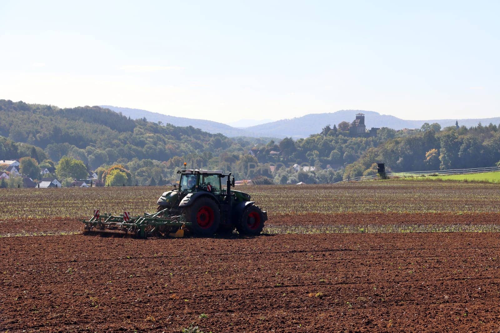 Landwirt eggt das Feld, im Hintergrund Burg Trendelburg, Hessen, Deutschland