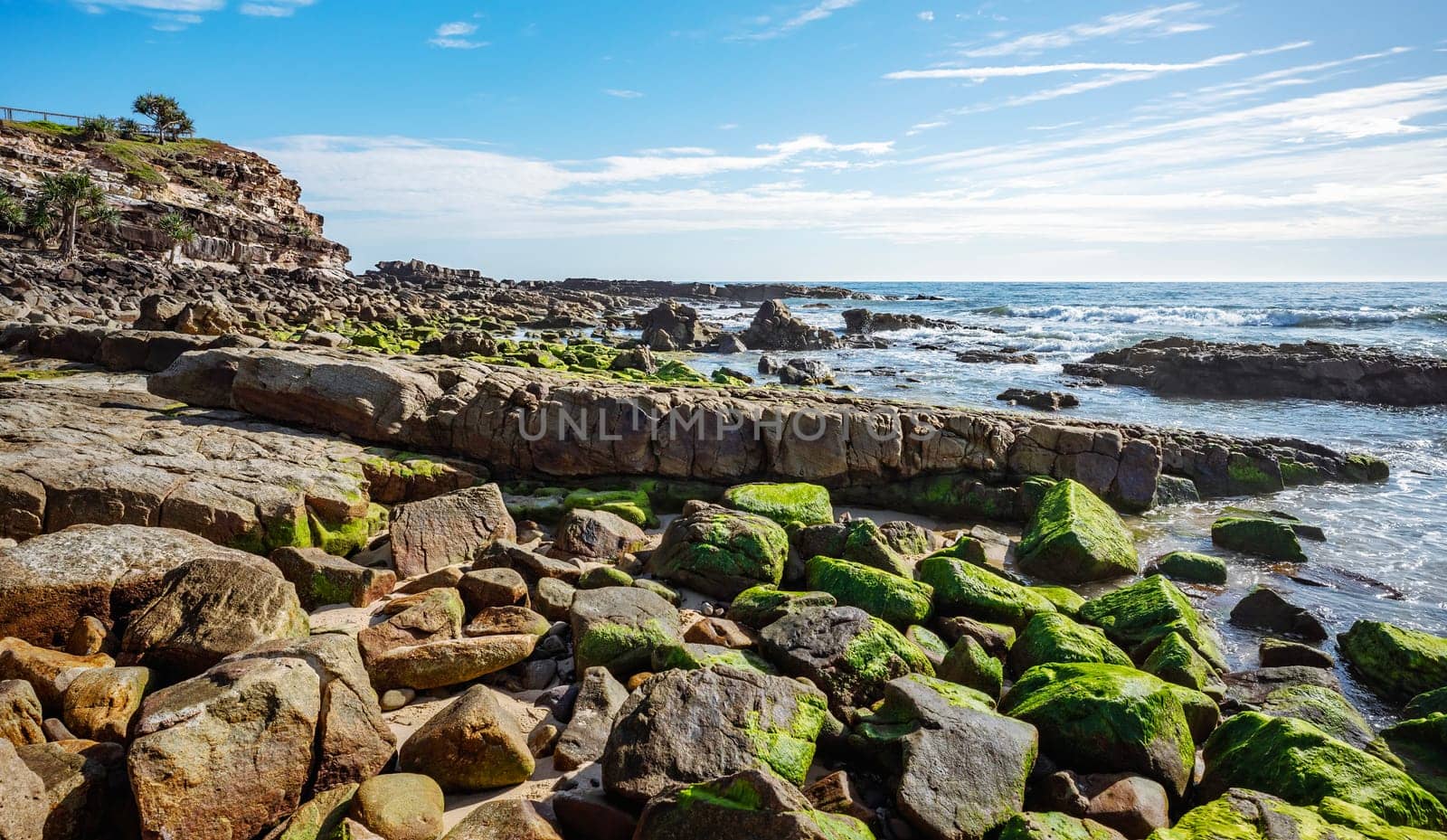 Lookout and rocky headland at Point Arkwright, Coolum, Sunshine Coast, Queensland, on a sunny day with blue cloudy sky and blue water