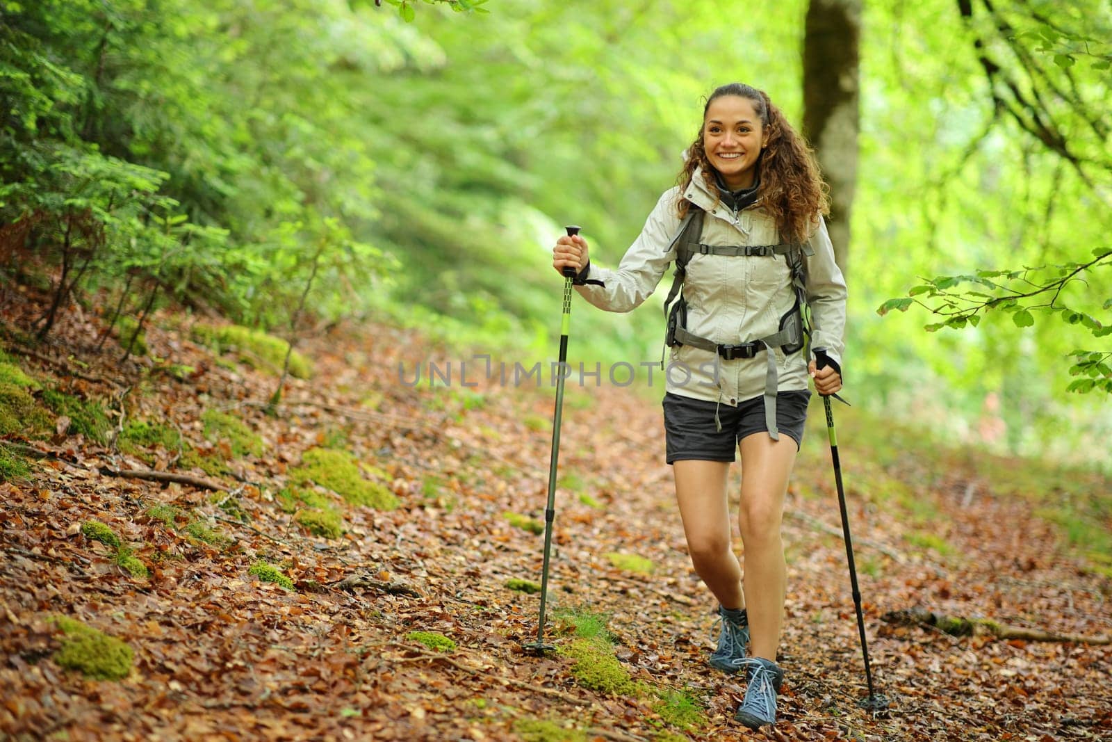 Front view portrait of a happy hiker walking in a forest