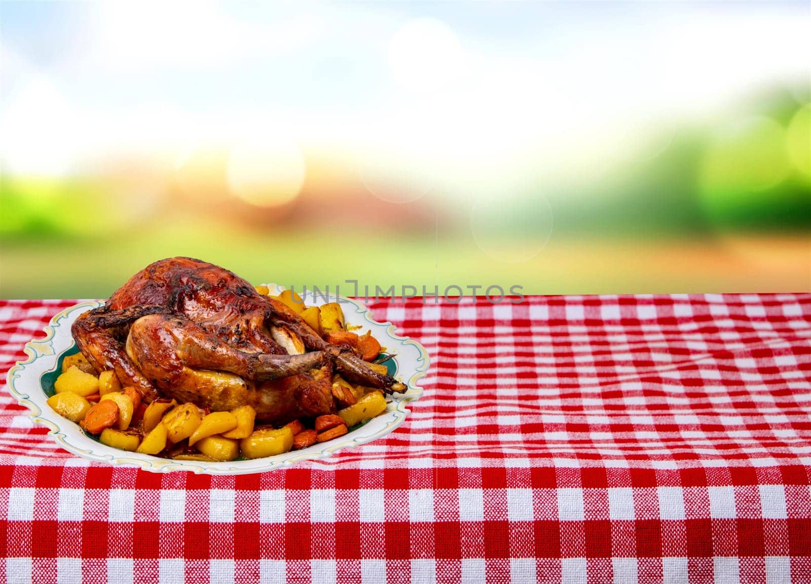 Grilled whole guinea fowl or baked pearl chicken on roasted potatoes and vegetables and port wine sauce is served on a beautiful plate on table over abstract natural background.
