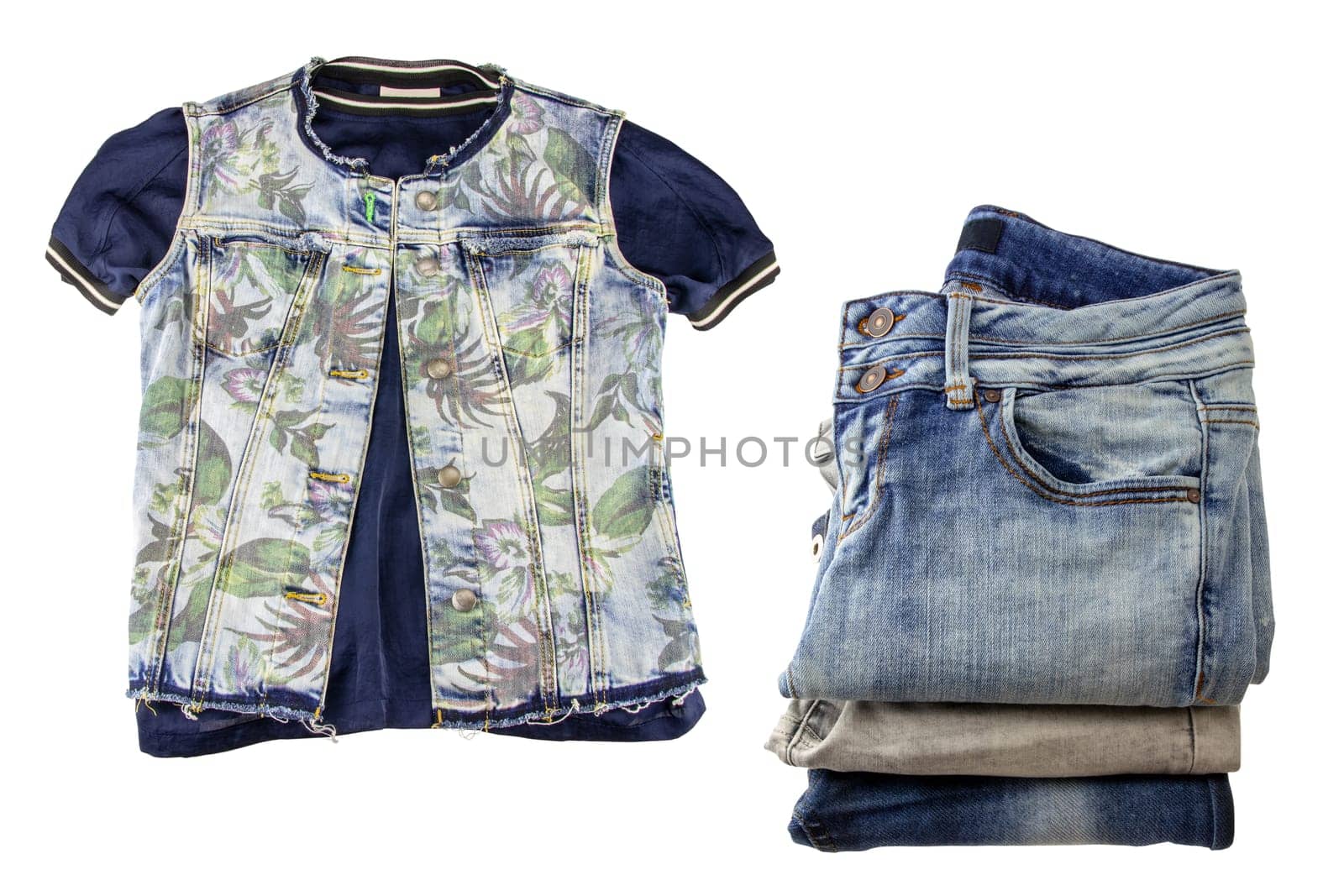 Women jeans fashion. A sleeveless blue jeans vest or jacket for woman on a blue shirt and a stack of denim pants isolated on a white background.