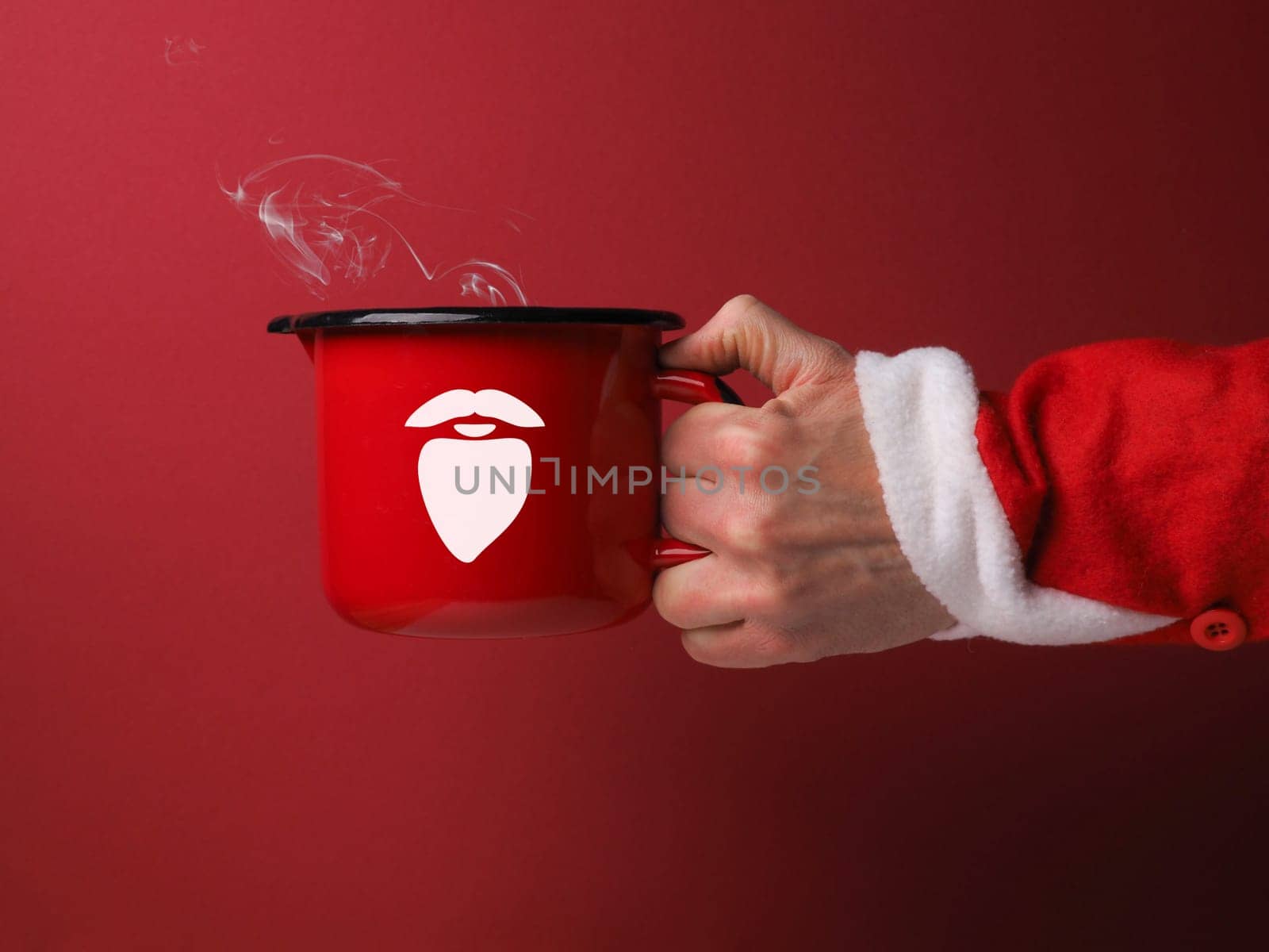 Hand of Santa with a big red cup of hot chocolate on a red background