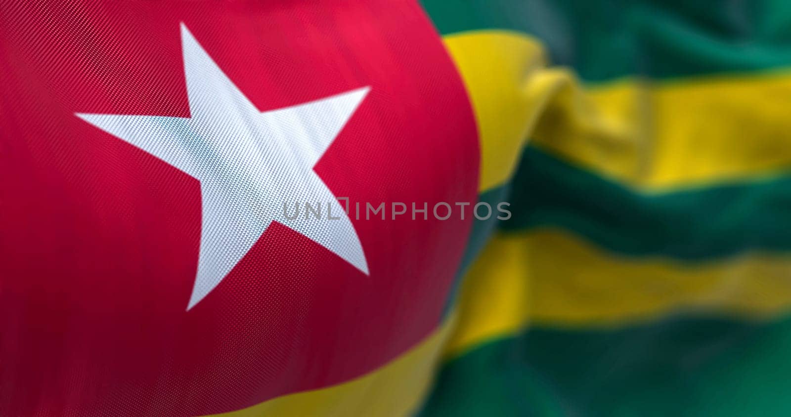 Close-up view of the Togo national flag waving in the wind. The Togolese Republic is a country in West Africa. Fabric textured background. Selective focus. 3d illustration