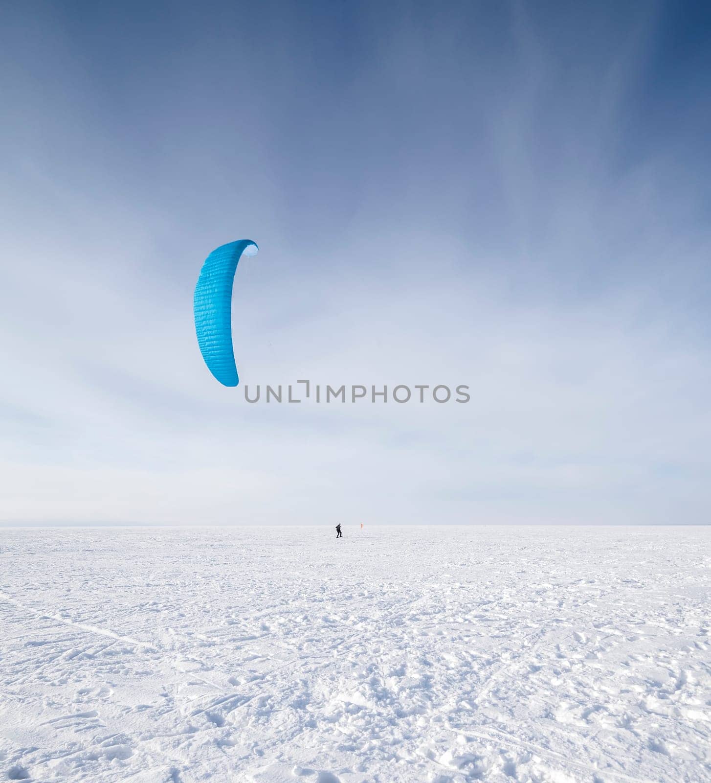 Kite surfer being pulled by his kite across the snow