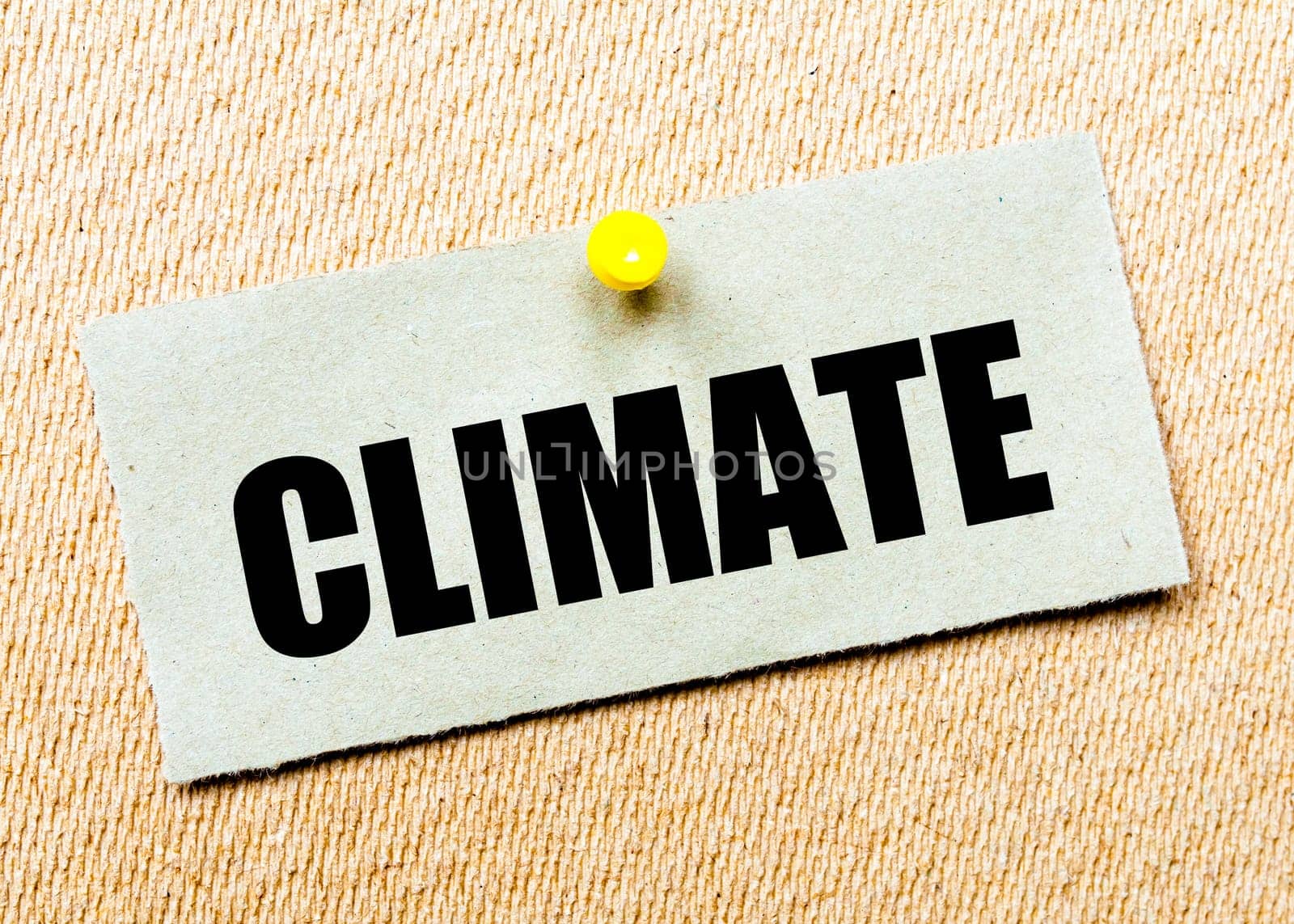 Recycled paper note pinned on cork board with word CLIMATE. Concept Image