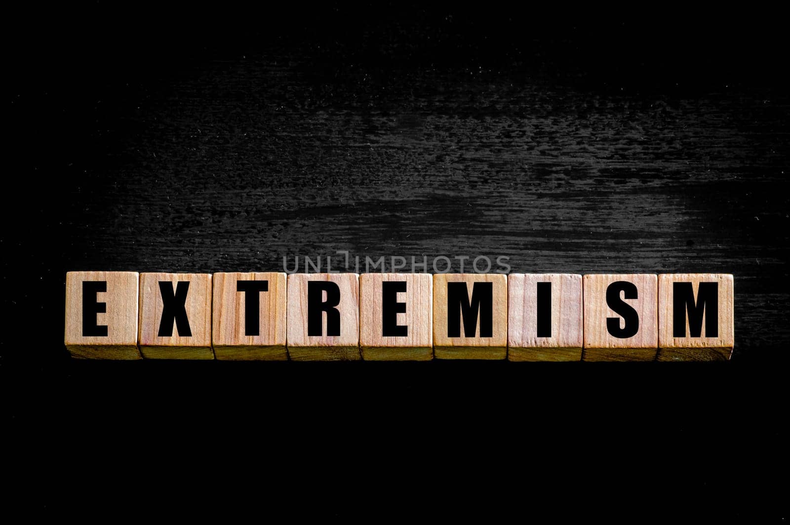 Word EXTREMISM  written on wooden small cubes with letters isolated on black background. Concept image with copy space available