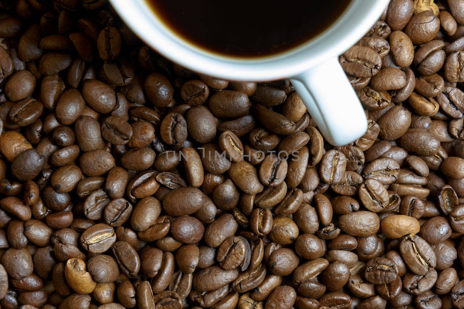 freshly roasted coffee beans and a cup of coffee on a table