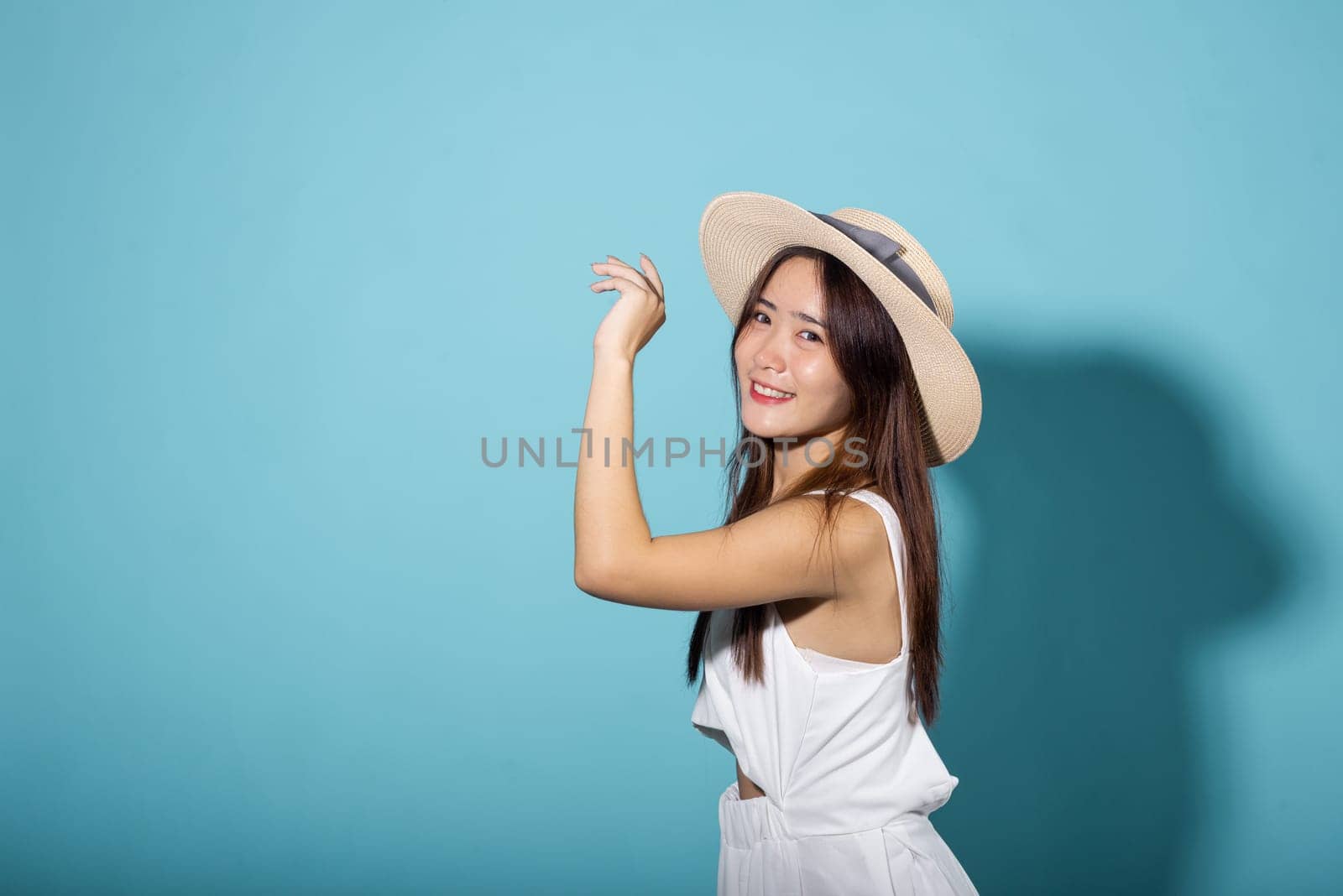 Portrait female raising arm and hand in protection and block sunshine, young woman hand up cover face protect sun light and UV in studio isolated on blue background, cosmetic sunscreen cream advertise