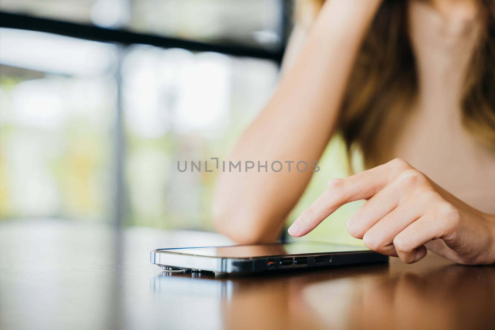 Beautiful Asian female has transfer money financial internet banking on mobile phone, young woman using smart phone for shopping online at cafe coffee shop near windows in the morning